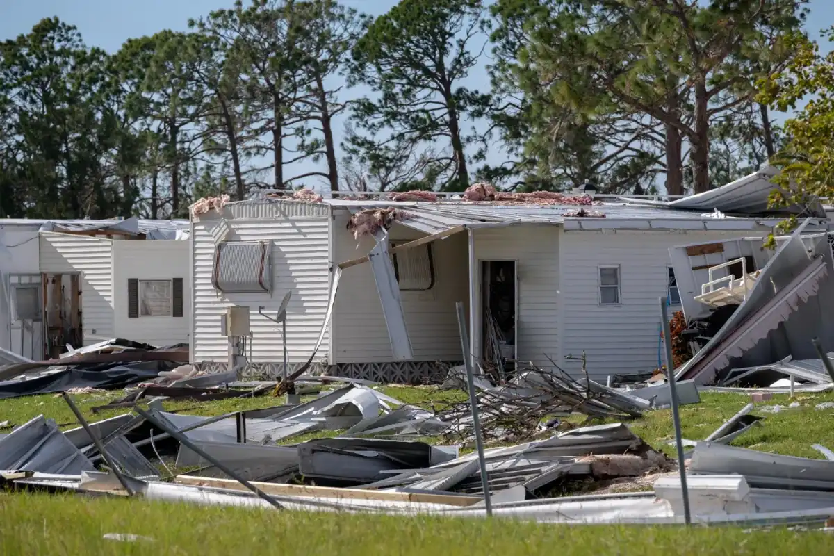 Storm-damaged mobile home with a destroyed roof and scattered debris